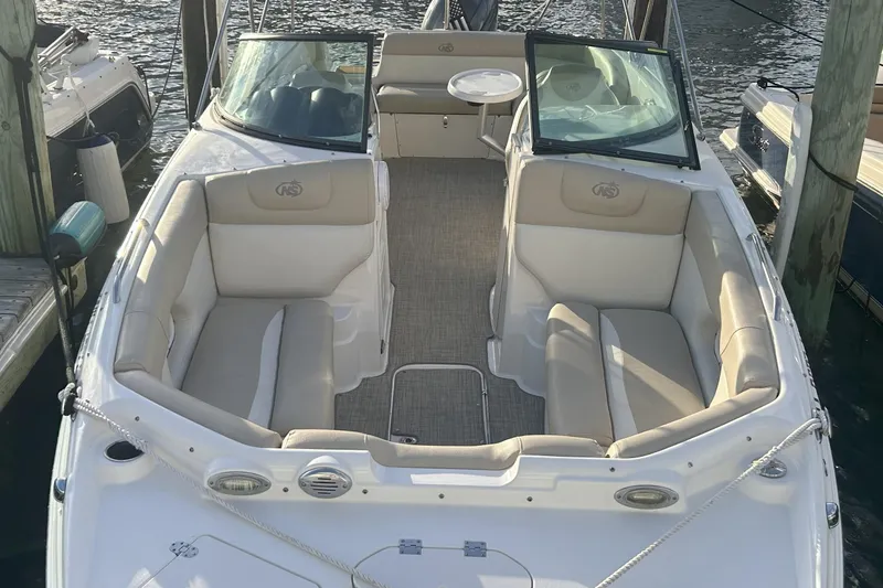 Slide: The Image of 2018 NauticStar 243DC Sport Deck boat with spacious seating, docked at marina. - 10