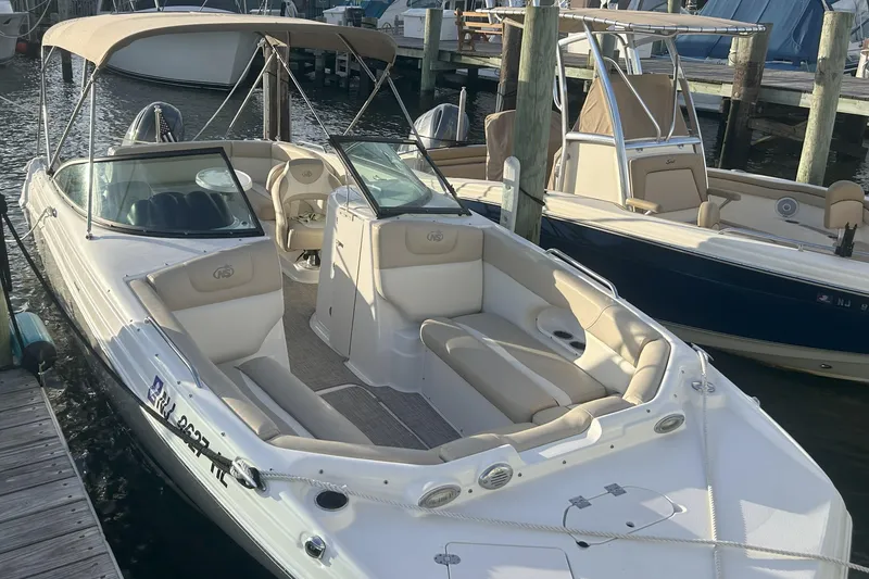 Slide: The Image of 2018 NauticStar 243DC Sport Deck boat docked at marina, featuring spacious seating and canopy. - 11