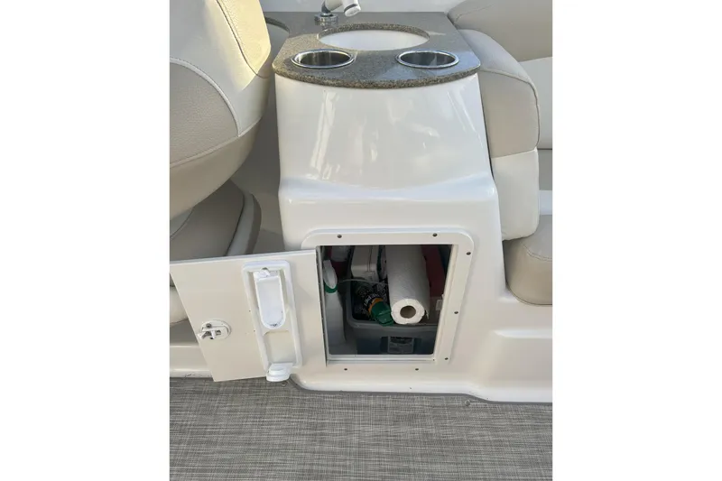 Slide: The Image of 2018 NauticStar 243DC Sport Deck storage compartment with open door and cup holders. - 12