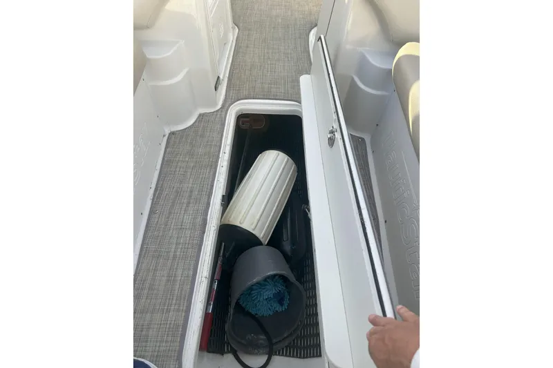 Slide: The Image of 2018 NauticStar 243DC Sport Deck storage compartment with cleaning supplies and equipment. - 13