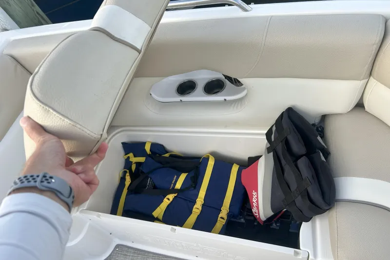 Slide: The Image of 2018 NauticStar 243DC Sport Deck seat storage with life jackets and accessories. - 17