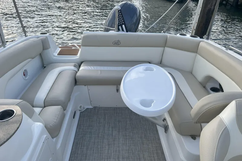 Slide: The Image of 2018 NauticStar 243DC Sport Deck boat interior with beige seating and round table. - 2