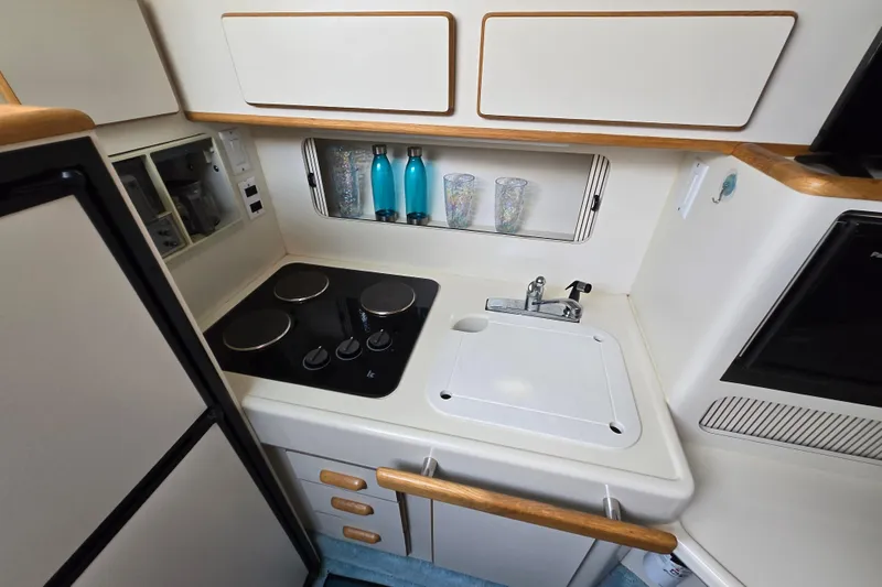 Slide: The Image of 1994 Sea Ray 400 Express Cruiser kitchen with stove, sink, and storage cabinets. - 15