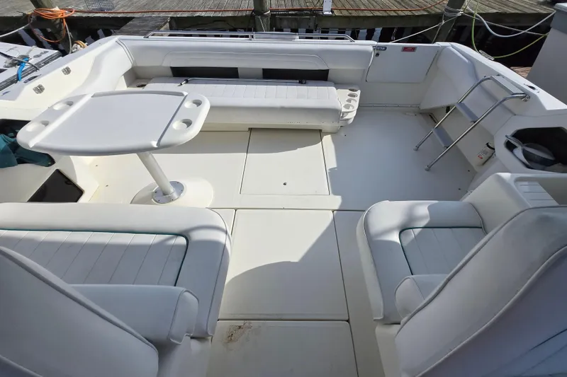 Slide: The Image of 1994 Sea Ray 400 Express Cruiser cockpit with white seating and table, docked at marina. - 2