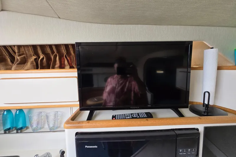 Slide: The Image of 1994 Sea Ray 400 Express Cruiser interior with TV, remote, and kitchen essentials. - 28