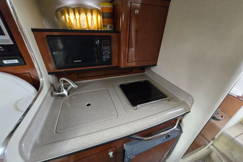 Slide: The Image of Compact kitchen area in a 2006 Sea Ray 280 Sundancer boat with sink and microwave. - 11