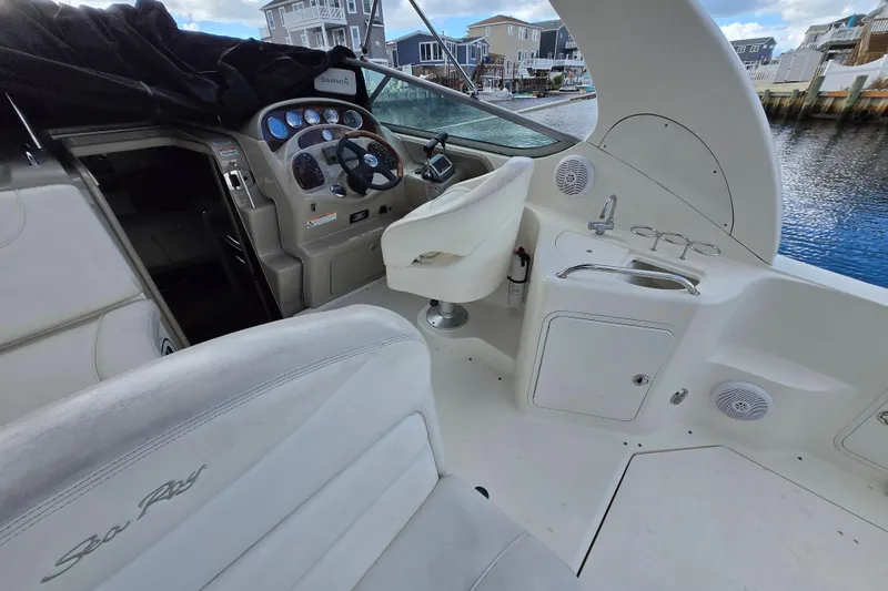 Slide: The Image of 2006 Sea Ray 280 Sundancer cockpit with steering wheel, controls, and seating by the water. - 4