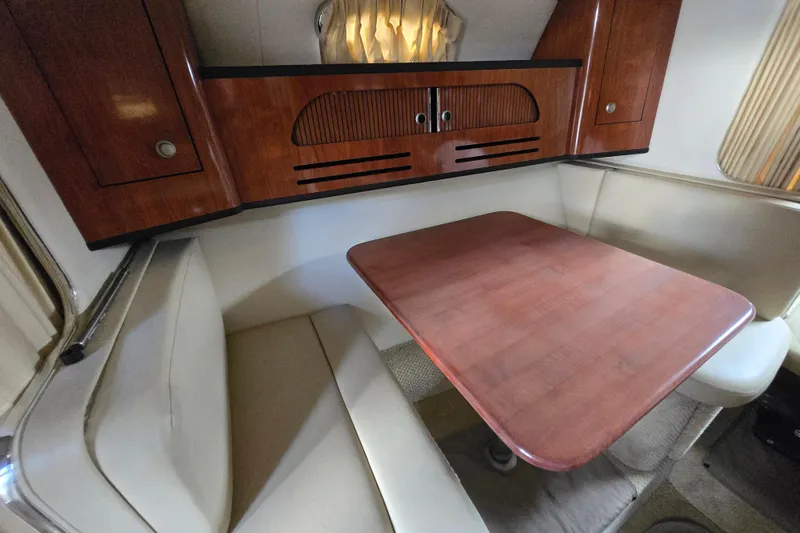 Slide: The Image of 2006 Sea Ray 280 Sundancer cabin interior with wooden table and cushioned seating. - 8