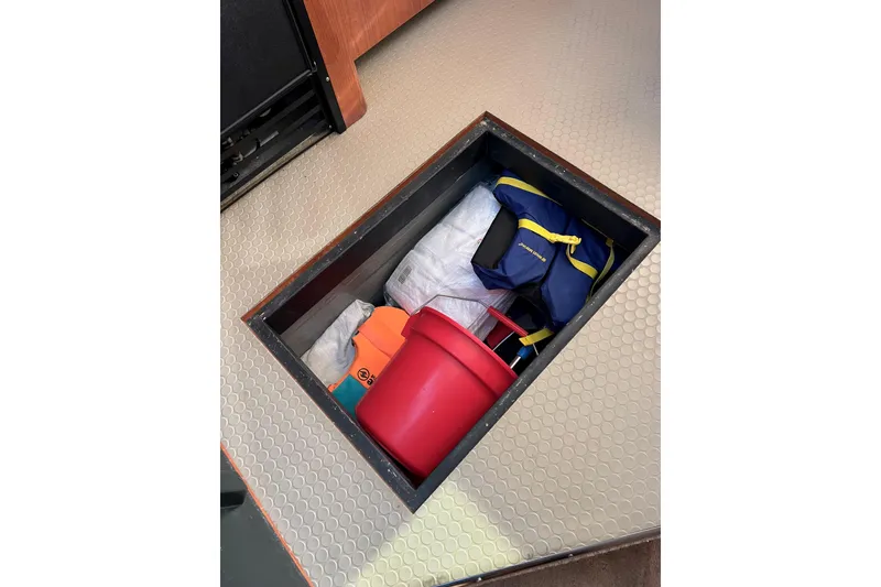 Slide: The Image of Storage compartment on 2000 Sea Ray 400 Sedan Bridge with life jacket and red bucket. - 106