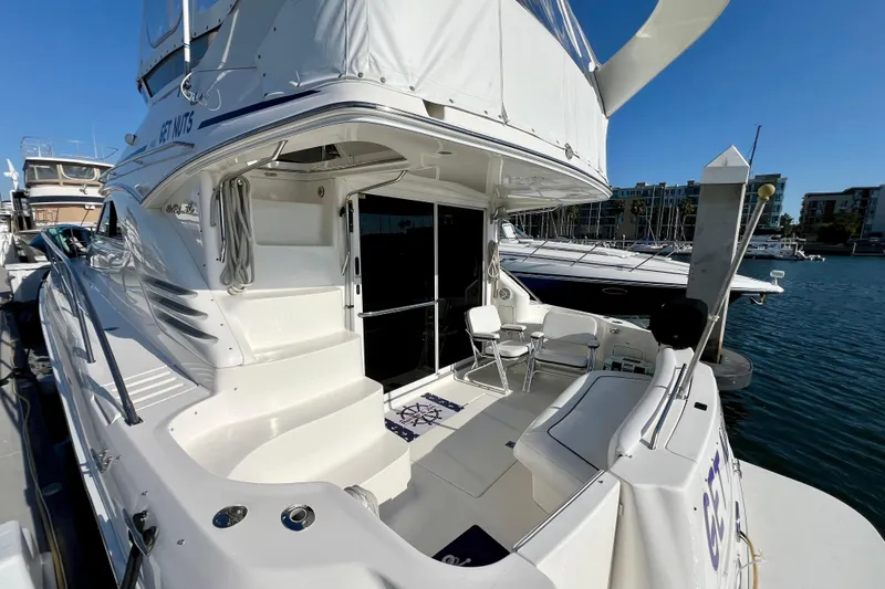 Slide: The Image of 2000 Sea Ray 400 Sedan Bridge yacht docked at marina, featuring spacious deck and seating. - 13