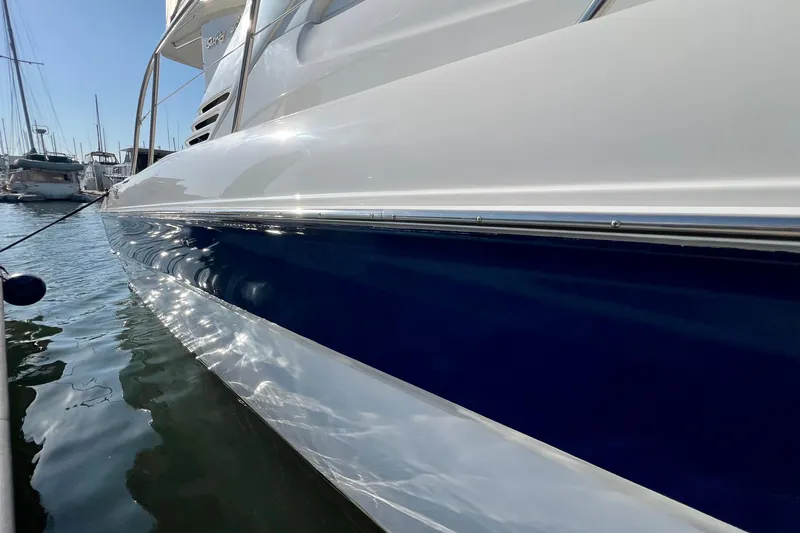 Slide: The Image of 2000 Sea Ray 400 Sedan Bridge yacht docked in marina, reflecting sunlight on water. - 4