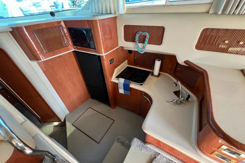 Slide: The Image of Interior of 2000 Sea Ray 400 Sedan Bridge yacht, featuring kitchen area with wood cabinetry. - 93