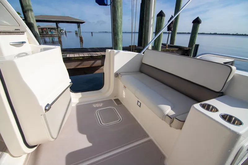 Slide: The Image of 2016 World Cat 320 DC boat interior with seating and cup holders by a dock. - 27