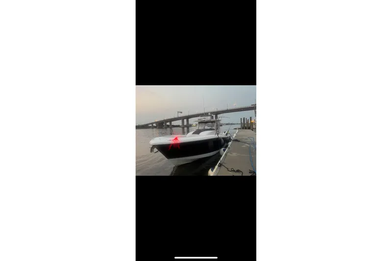 Slide: The Image of 2017 Edgewater 368CC boat docked near a bridge at sunset. - 20