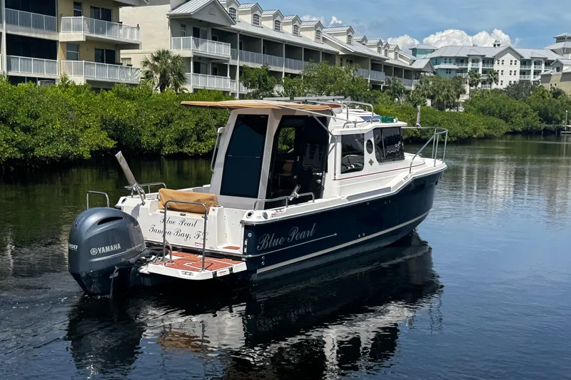 Slide: The Image of 2023 Ranger Tugs R-23 boat on calm water near residential buildings. - 2