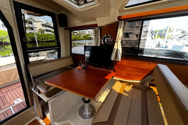 Slide: The Image of 2023 Ranger Tugs R-23 interior with dining area, wooden table, and large windows. - 5