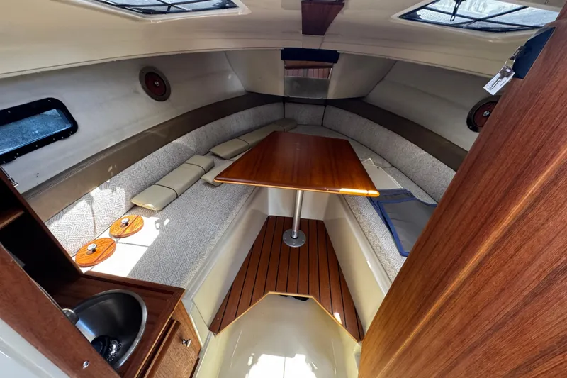 Slide: The Image of 2023 Ranger Tugs R-23 cabin interior with wood table, seating, and sink. - 9