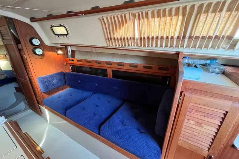 Slide: The Image of Interior of 1985 O'Day 35 sailboat with blue cushioned seating and wooden cabinetry. - 10