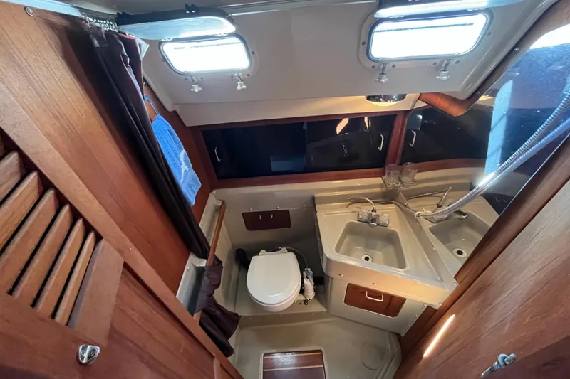 Slide: The Image of 1985 O'Day 35 yacht bathroom with wooden cabinetry, dual sinks, and a compact toilet. - 11