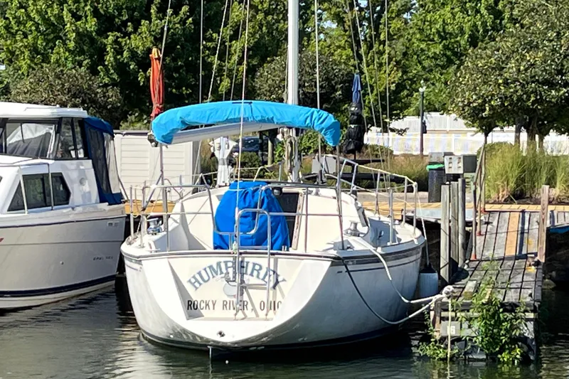 Slide: The Image of 1985 O'Day 35 sailboat docked at marina, featuring blue canopy and lush surroundings. - 14