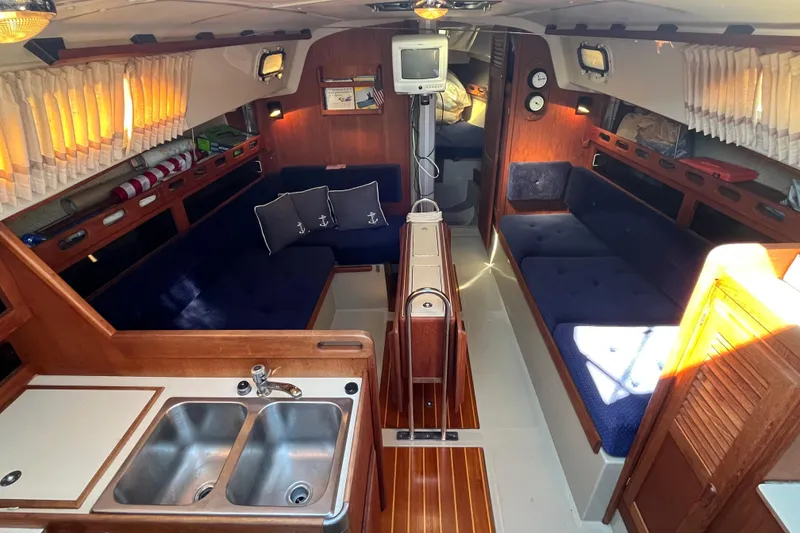 Slide: The Image of Interior of a 1985 O'Day 35 sailboat with cozy seating and a compact kitchen area. - 4