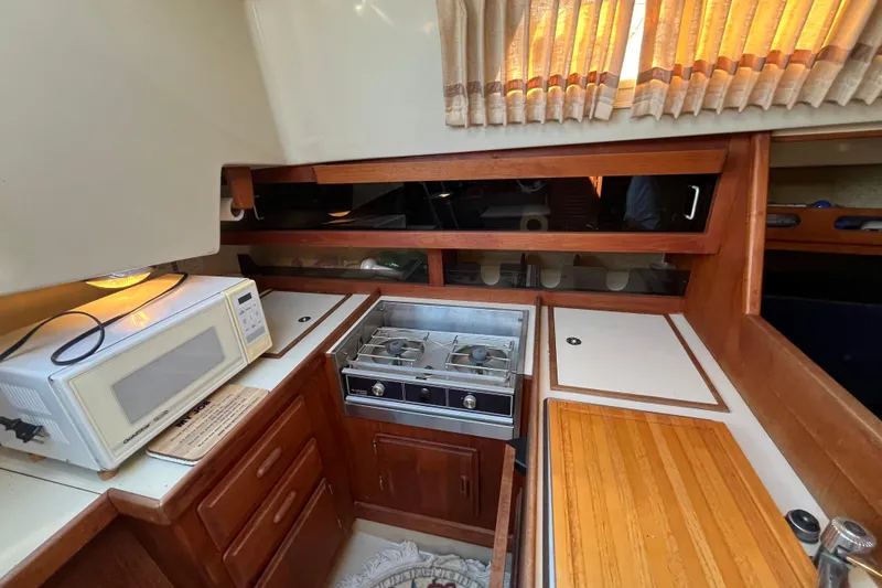 Slide: The Image of 1985 O'Day 35 yacht kitchen with stove, microwave, and wooden cabinetry. - 5
