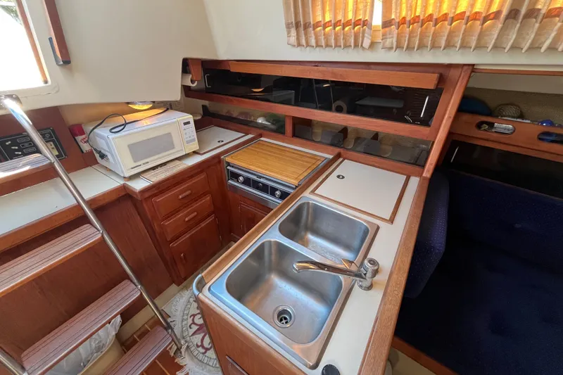 Slide: The Image of 1985 O'Day 35 yacht interior kitchen with sink, microwave, and wooden cabinetry. - 6