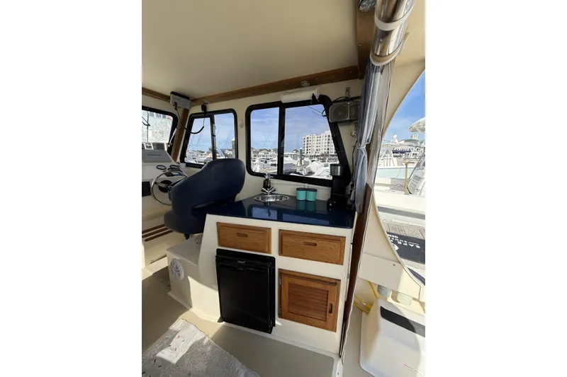 Slide: The Image of Interior of 2020 Eastern Islander 270 boat with helm, kitchenette, and marina view. - 14