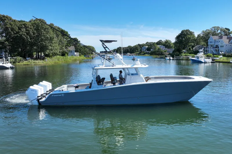 The Image of 2025 Freeman 42 LR boat cruising on a scenic river with lush greenery and houses. - 1