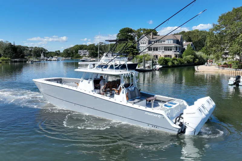 Slide: The Image of 2025 Freeman 42 LR boat cruising in a scenic waterfront setting with luxury homes. - 15