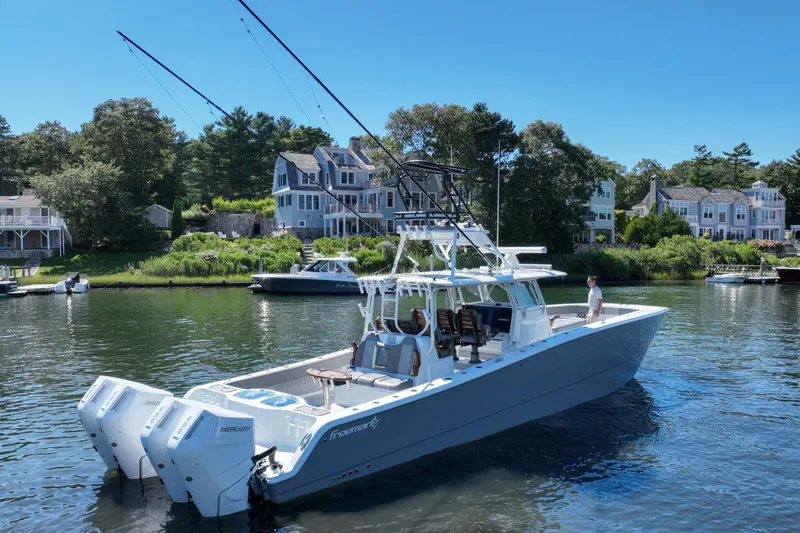 Slide: The Image of 2025 Freeman 42 LR boat on water near waterfront homes, featuring dual Mercury engines. - 6