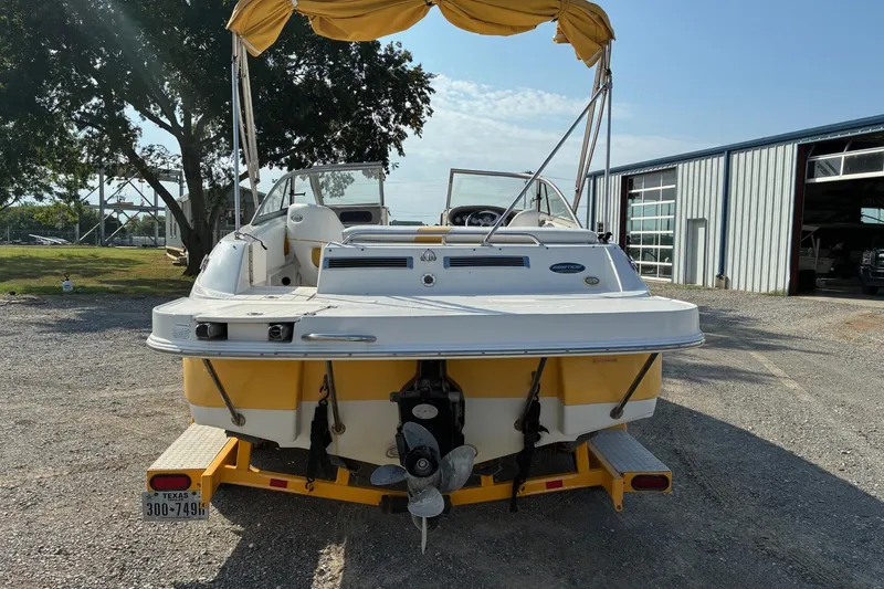 Slide: The Image of 2004 Ebbtide Campione 210 boat with yellow accents, parked outdoors near a metal building. - 2