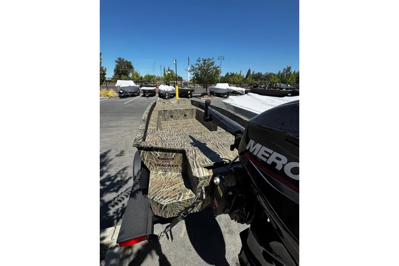 Slide: The Image of 2026 Tracker Grizzly 1650 T Prairie Wings Edition boat with camouflage design in parking lot. - 2