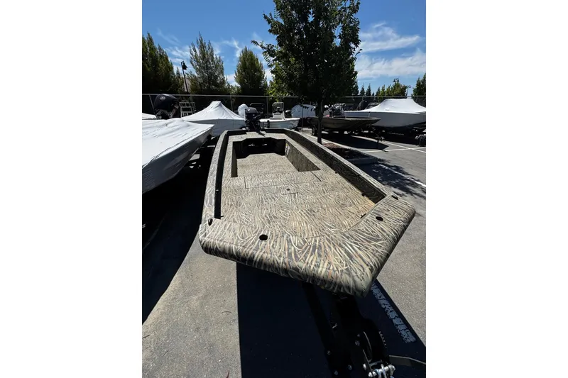 Slide: The Image of 2026 Tracker Grizzly 1650 T Prairie Wings Edition boat in parking lot, camo design. - 3