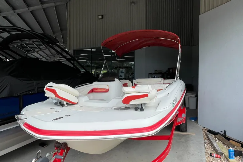 Slide: The Image of 2007 Tahoe 195s boat with red accents and canopy in storage. - 2