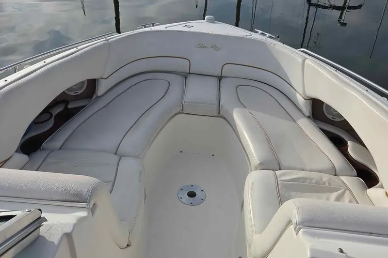 Slide: The Image of 1999 Sea Ray 280 Bow Rider with white cushioned seating, docked on calm water. - 2