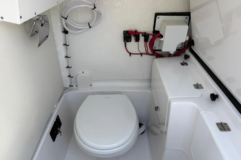 Slide: The Image of 2026 Tidewater 256 CC Adventure boat interior with compact marine toilet and storage. - 26