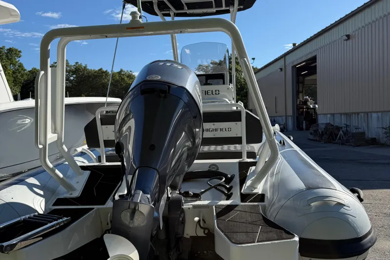 Slide: The Image of 2024 Highfield Sport 560 boat with powerful outboard motor, docked near a warehouse. - 11