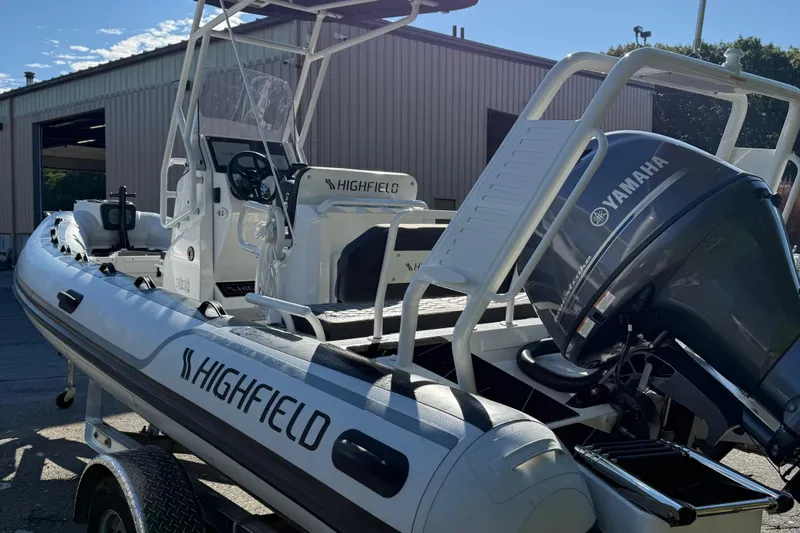 Slide: The Image of 2024 Highfield Sport 560 boat with Yamaha engine, parked outside a warehouse. - 12