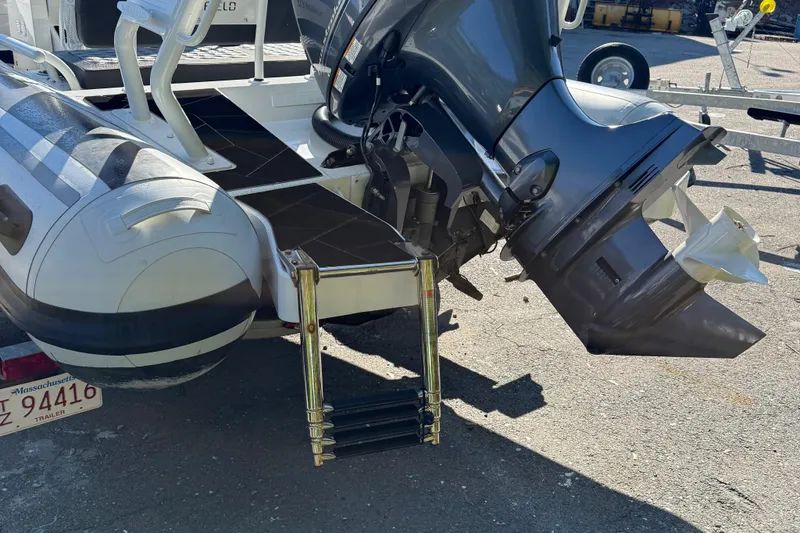 Slide: The Image of 2024 Highfield Sport 560 boat with outboard motor and ladder, parked on a trailer. - 13