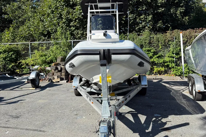 Slide: The Image of 2024 Highfield Sport 560 boat on trailer, parked outdoors with greenery background. - 36