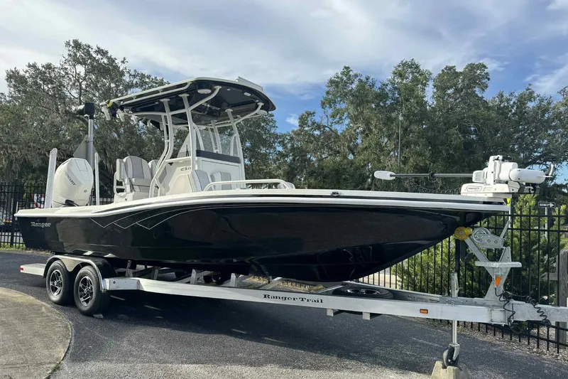 The Image of 2026 Ranger 2510 Bay boat on trailer, parked outdoors with trees in background. - 0