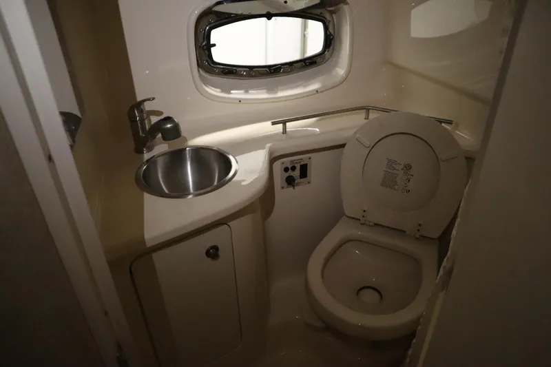Slide: The Image of 2013 Sea Ray 280 Sundancer bathroom with sink, toilet, and porthole window. - 56