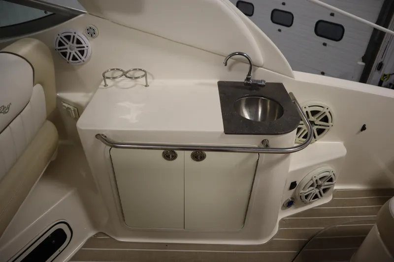 Slide: The Image of 2013 Sea Ray 280 Sundancer boat interior with sink, speakers, and storage cabinet. - 71