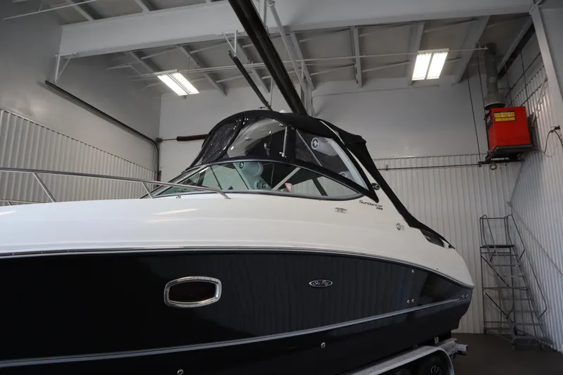 Slide: The Image of 2013 Sea Ray 280 Sundancer boat in indoor storage, showcasing sleek design and black hull. - 85