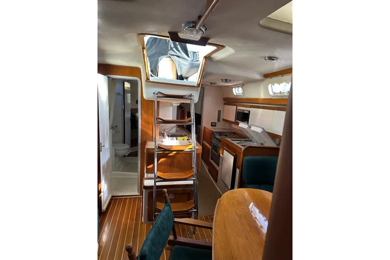 Slide: The Image of Interior of 1997 Catalina Morgan 38 sailboat, featuring kitchen, dining area, and ladder to deck. - 42