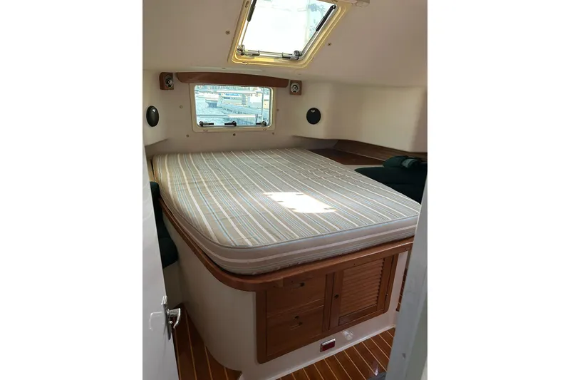 Slide: The Image of 1997 Catalina Morgan 38 cabin interior with bed, window, and wooden storage. - 49