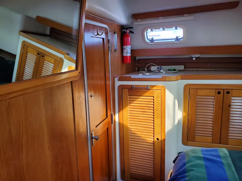Slide: The Image of Interior of 1997 Catalina Morgan 38 sailboat with wooden cabinets and a small window. - 58