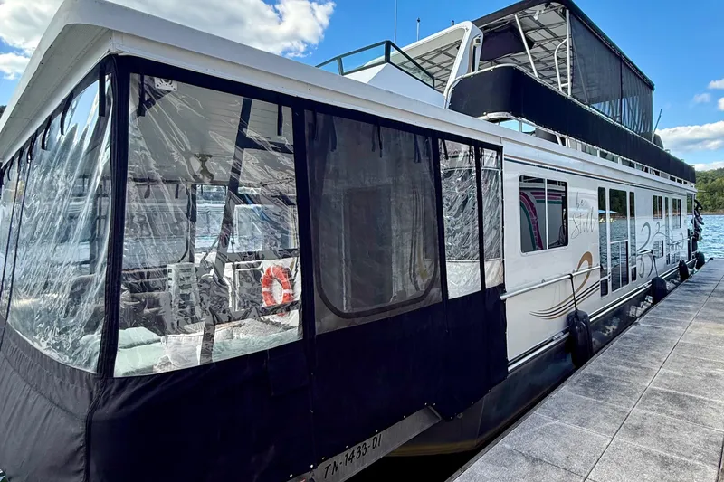 The Image of 2003 Horizon houseboat docked on a sunny day, featuring clear enclosures and upper deck. - 1