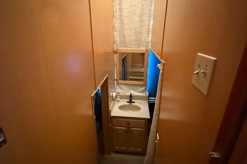 Slide: The Image of Compact bathroom in a 2003 Horizon houseboat with sink, mirror, and wooden cabinetry. - 19